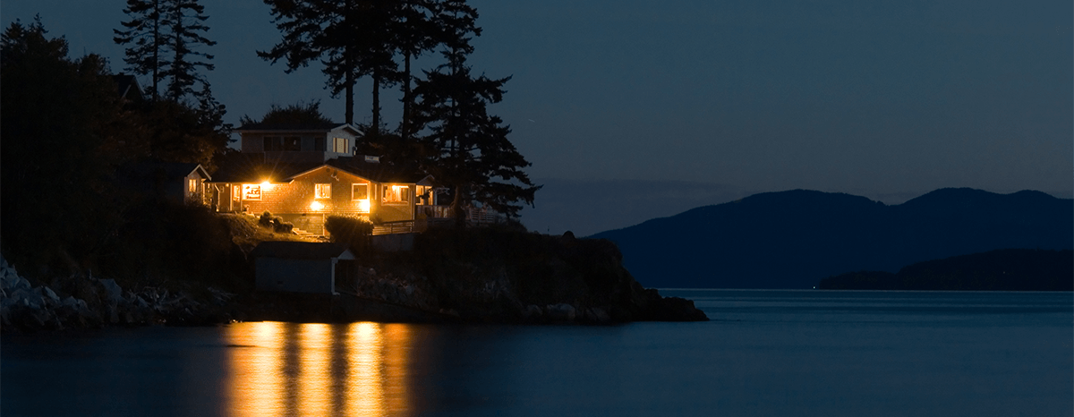 Lake house on the left at night with all the lights on.